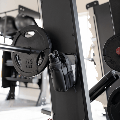 Titan Gym Bag by HolyH₂O™ attached to gym equipment, showcasing its magnetic gym bag feature for convenience.