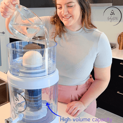 A woman pouring water into the HolyH₂O™ Trinity Filter, showcasing its high-volume capacity and innovative design.